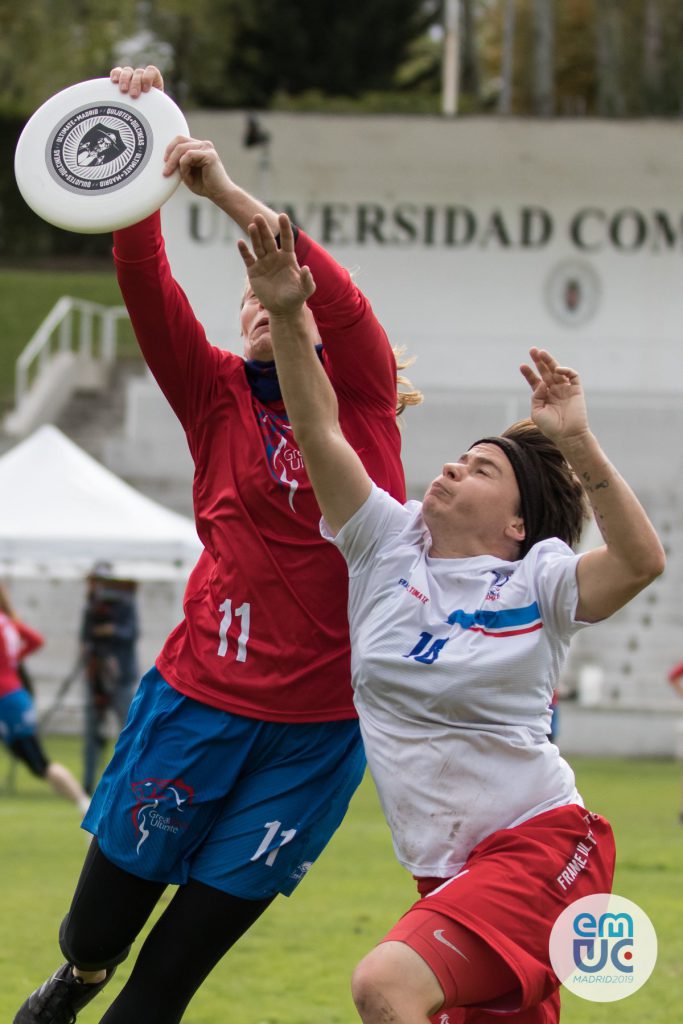 Jenna catching a disc in the air, unfazed by pressure from Aline Mondiot of France. 